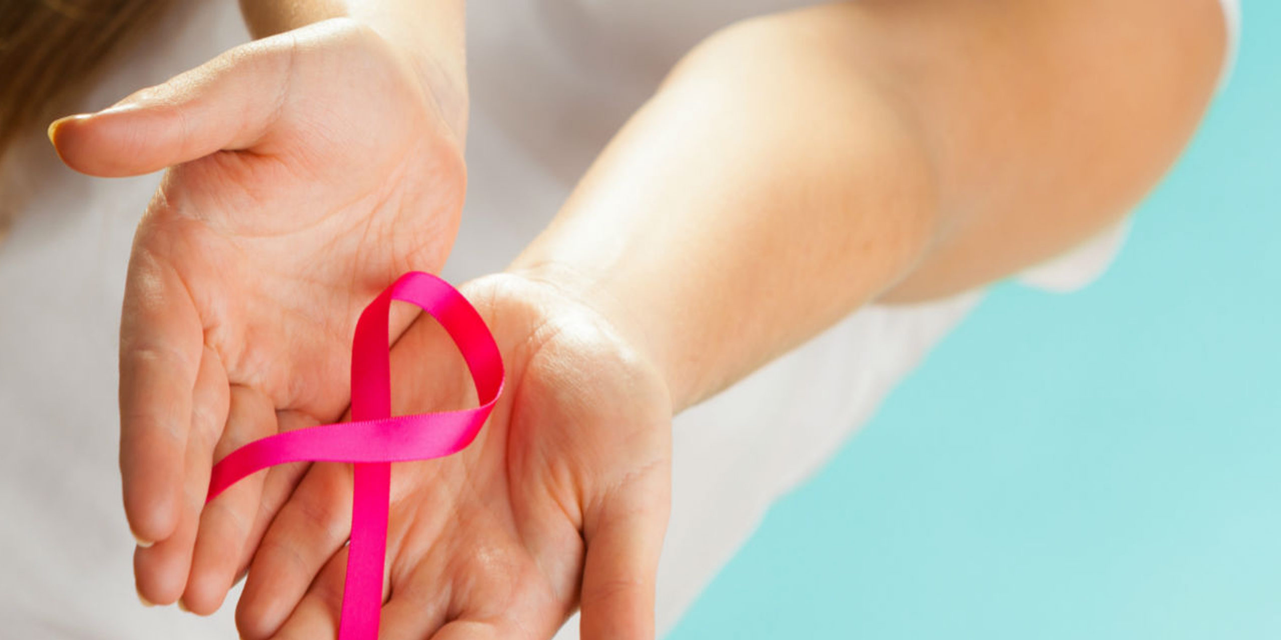 Women hand holding pink colour breast cancer awareness ribbon