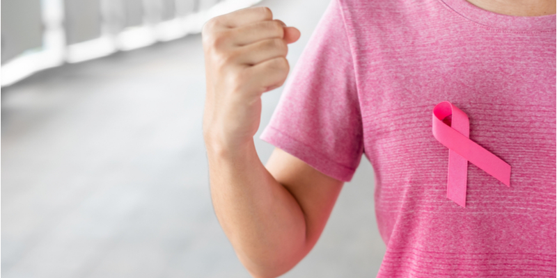 Close up of a woman wearing a pink T-shirt with a pink ribbon in support of breast cancer awareness.