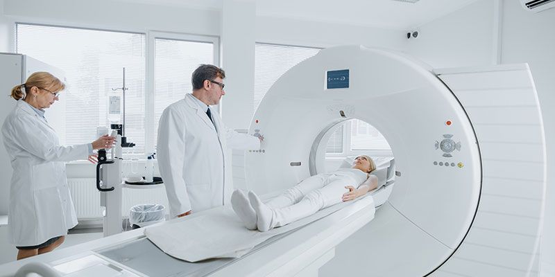 A radiographer is operating a CT scanner for a female patient.